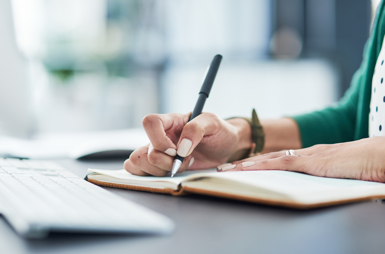 A businesswoman writes in a notebook, demonstrating how to write great business copy