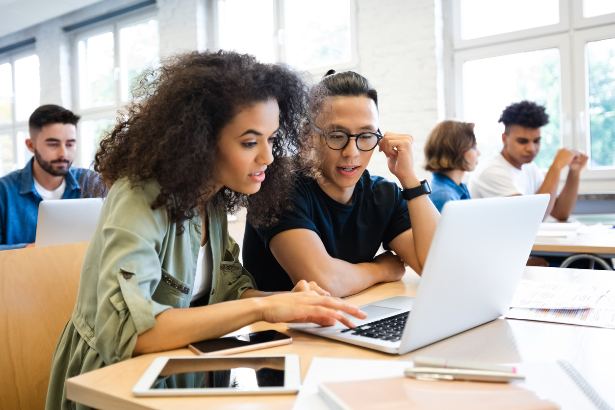 College students huddle over a laptop, getting news