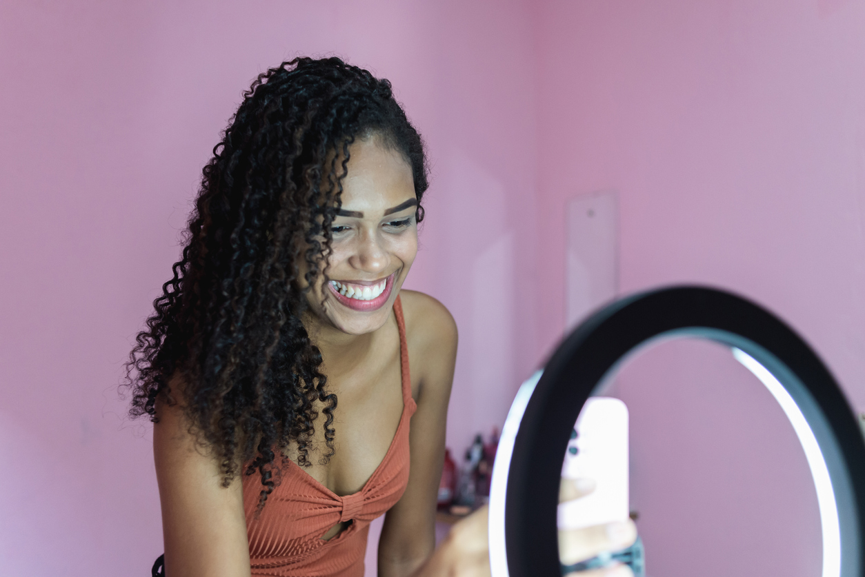 Black young woman filming herself dancing at home to share on social media