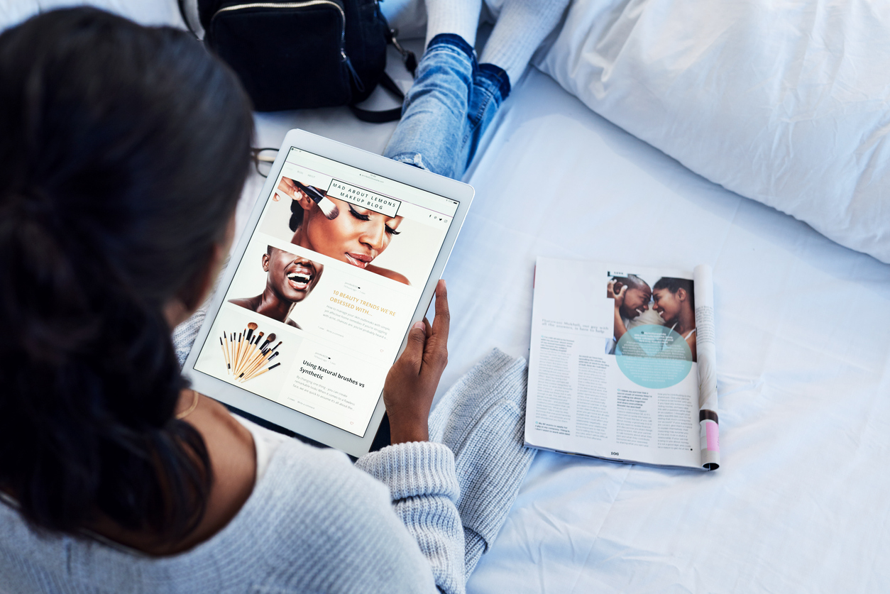 High angle shot of an unrecognizable woman using a tablet while chilling on her bed in her bedroom at home. New influencers are inspiring women who crave content like magazines offer but more directly.