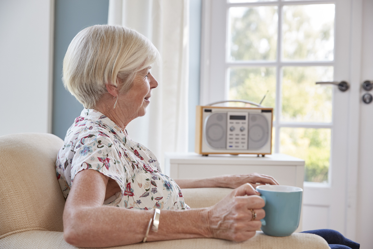 Senior woman drinking tea and listening to radio at home. Penn Medicine has a radio ad to encourage listeners with chronic pain.