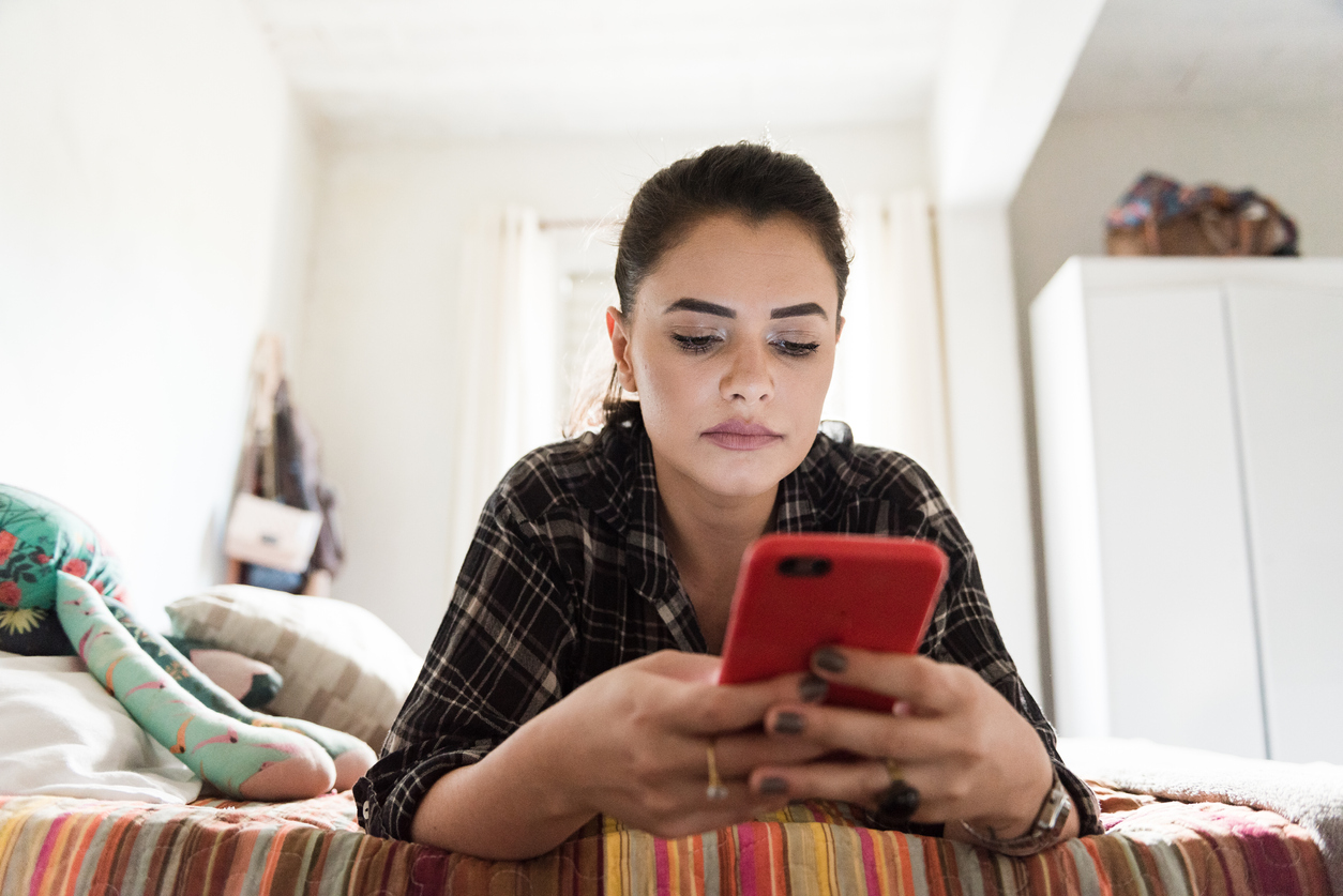 Smiling woman using smartphone in bed Brands are not fully getting Gen Z's humor.